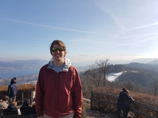 Colin smiling with a Swiss mountain behind him