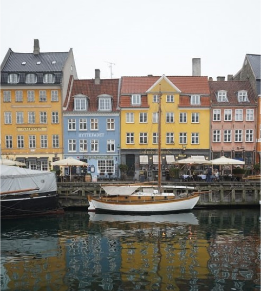 A boat sitting in front of buildings in Nyhavn harbour, Denmark