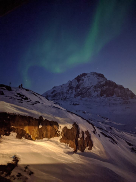 The aurora borealis above a snowy Greenland mountain