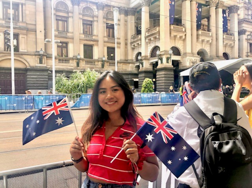 Pamira smiling while holding Australian flags in each hand.
