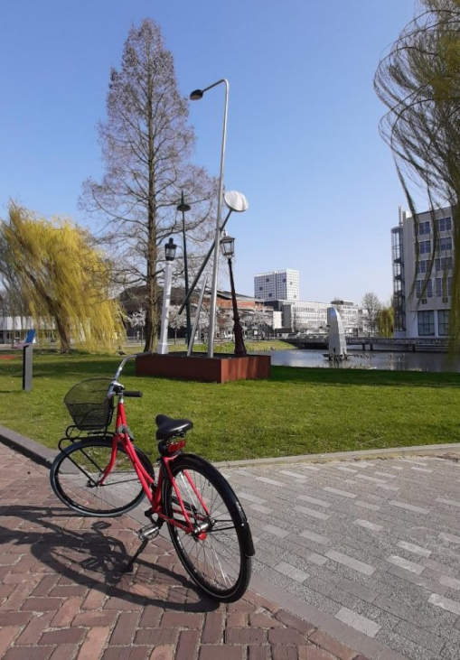 A red bike sitting on the Delft University of Technology campus