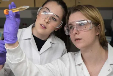 Two students working in a lab and looking at a mixed solution
