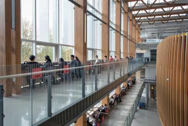 Photo of students sitting along desks by windows on the 3rd floor of the Nest