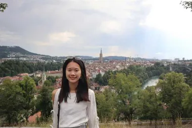 A student smiling at the camera with the city skyline in the background