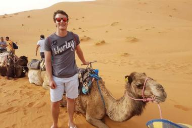 Student beside a camel on a desert excursion