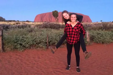 A student piggybacking another student in the red rock area of Southwestern United States.