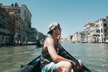 A student sitting in a boat in a canal looking at the architecture in a European city 