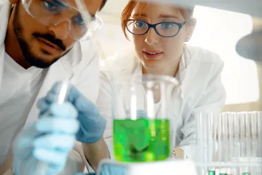 2 students examining green liquid