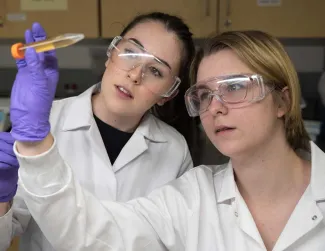 Two students in a lab looking at a solution in a tube