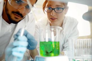 Two students examine green liquid
